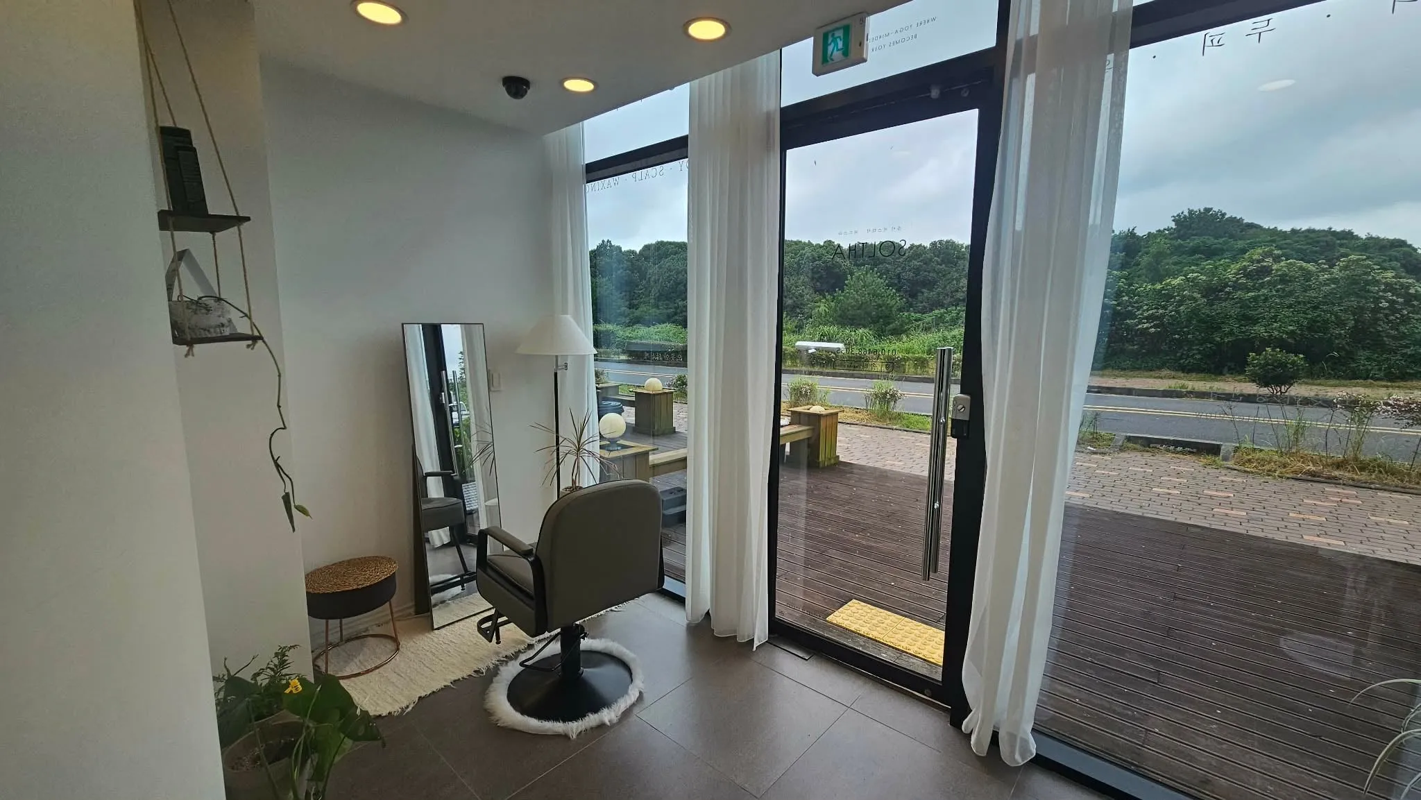 Inside SOLTHA — a single chair, sheer curtains, and the green of Jeju beyond the glass
